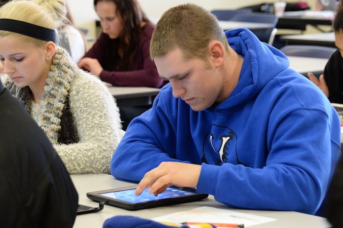 A male student using his tablet in a classroom